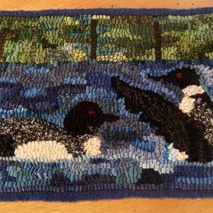 Hand hooked wool rug of two loons on a lake with trees in the background