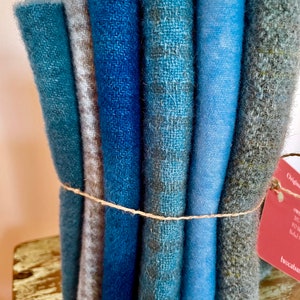 Blue wool collection bundled together with linen thread, a red tag attached and sitting on a chippy stool