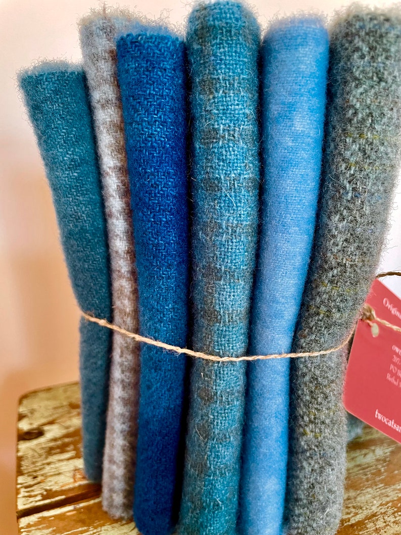 Blue wool collection bundled together with linen thread, a red tag attached and sitting on a chippy stool