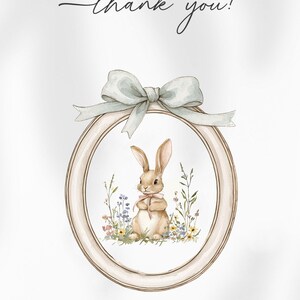 May include: A thank you card featuring a watercolour illustration of a brown bunny rabbit sitting in a field of flowers. The bunny is holding a pink flower in its paws. The illustration is surrounded by a light brown oval frame with a blue ribbon.