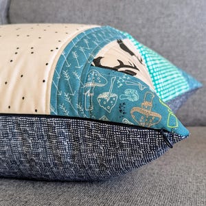 May include: A blue and white patterned pillow with a black and white deer design. The pillow has a zipper closure and a dark blue fabric backing.
