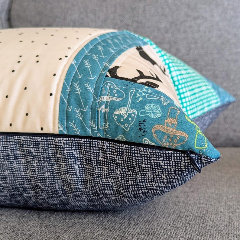 May include: A blue and white patterned pillow with a black and white deer design. The pillow has a zipper closure and a dark blue fabric backing.