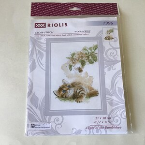 May include: A cross-stitch kit featuring a sleeping kitten with a bumblebee and flowers. The kit includes wool and acrylic threads. The design is 8 1/4" x 11 7/8" and is titled "Flight of the Bumblebee". The kit is packaged in a clear plastic bag.