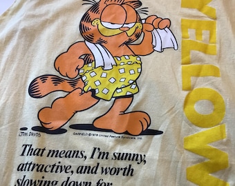 May include: Yellow tank top featuring Garfield the cat in a yellow and white outfit. The text reads "My favorite color is: YELLOW" and "That means, I'm sunny, attractive, and worth slowing down for."