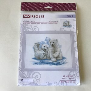 May include: A cross-stitch kit by Riolis featuring two polar bear cubs on ice. The kit includes wool and acrylic materials. The finished design measures 15 3/4" x 11 3/4". The packaging includes the text "Bear Cubs on Ice".