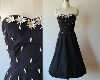 Vestido de cóctel negro sin tirantes con escote corazón, corte entallado y falda acampanada, estampado floral y pedrería, estilo años 50, talla extra pequeña.