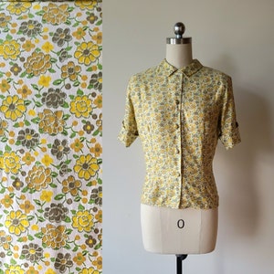 Op de afbeelding: Een geel en bruin bloempatroon knoopshirt met een kraag en korte mouwen. Het shirt is op een wit mannequin.
