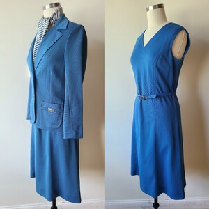 May include: Two-piece teal suit with a blazer, skirt, and a striped scarf. The blazer has a notched collar, a single button closure, and pocket details. A teal sleeveless dress with a V-neck and a matching belt is also displayed.