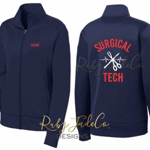 May include: Navy blue fleece jacket with a zipper closure. The back of the jacket has a white design that says "SURGICAL TECH" with a heartbeat line and a pair of scissors. The front of the jacket has a space for a name.