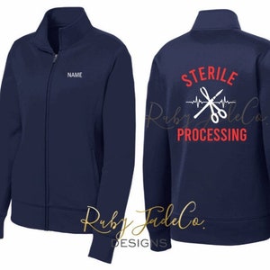 May include: Navy blue zip-up jacket with a white embroidered design on the back that says "STERILE PROCESSING" with a heartbeat line and crossed scissors. The front of the jacket has a blank space for a name.