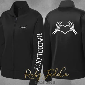 May include: Black zippered jacket with a white skeleton hand heart design on the back and the word "RADIOLOGY" spelled out with bones on the left sleeve. The jacket has a name tag on the left chest.