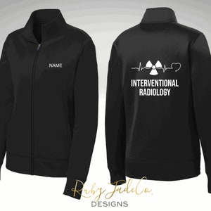 May include: Black zippered jacket with a white graphic on the back that says "INTERVENTIONAL RADIOLOGY" with a heart and a radiation symbol. The front of the jacket has a white name tag that says "NAME".