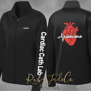 May include: Black zippered jacket with a white heart and EKG graphic on the back and the text "Cardiac Cath Lab" on the sleeve. The jacket has a white "name" tag on the front.