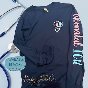 May include: Navy blue long-sleeve shirt with a stethoscope and footprints inside a heart on the front. The text "Neonatal ICU" is printed on the right sleeve in pink and blue.