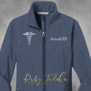 May include: A blue soft-shell jacket with a white zipper and a silver medical symbol embroidered on the left chest. The text "Sarah RN" is embroidered on the right chest.