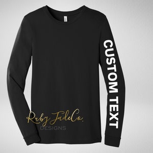 May include: Black long-sleeve shirt with white text on the sleeve that says "CUSTOM TEXT".