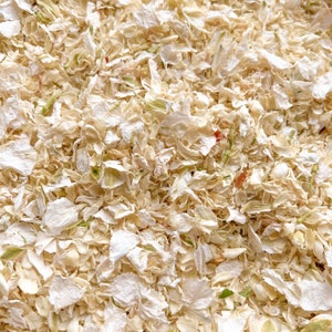 Op de afbeelding: Een close-up afbeelding van gedroogde witte bloemblaadjes, perfect voor bruiloftsdecoraties of knutselprojecten.
