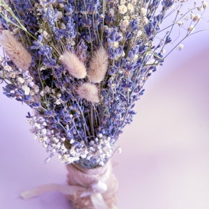 Op de afbeelding: Een boeket gedroogde lavendel- en gipskruidbloemen, gebonden met een wit lint en verpakt in jute.