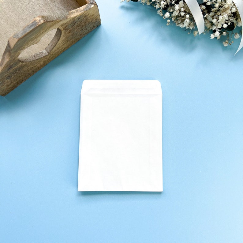 Op de afbeelding: Een witte envelop op een lichtblauwe achtergrond. De envelop is leeg en heeft een klep aan de bovenkant.