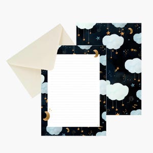 May include: A set of stationery featuring a cream-colored envelope and two sheets of lined paper. The paper has a dark navy blue background decorated with light blue clouds, golden crescent moons, and hanging stars in a celestial night sky pattern.