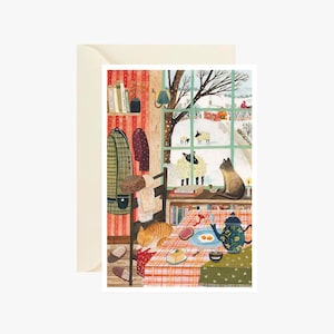 Pode incluir: Uma ilustração acolhedora de um quarto com uma janela com vista para uma paisagem nevada. No interior, um gato está sentado perto da janela e uma mesa está posta para o pequeno-almoço. Um cabide e uma estante são visíveis, criando uma cena acolhedora e convidativa. O cartão está num envelope creme.