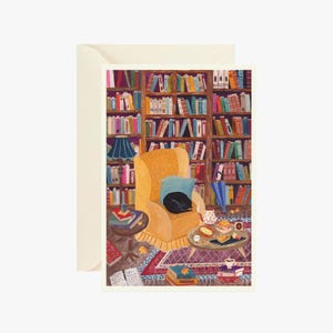 Op de afbeelding: Een wenskaart met een illustratie van een gele fauteuil met een zwarte kat en een blauw kussen, voor een hoge houten boekenkast vol kleurrijke boeken. Een kleine ronde tafel bevat eten en een kleed bedekt de vloer.