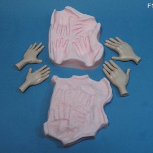 May include: A set of silicone moulds for making hand-shaped decorations. The moulds are pink and feature a variety of hand shapes. There are also five separate hand-shaped moulds in a skin tone colour.