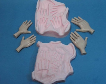 May include: A set of silicone moulds for making hand-shaped decorations. The moulds are pink and feature a variety of hand shapes. There are also five separate hand-shaped moulds in a skin tone colour.