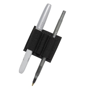 May include: Black nylon pen holder with two pens inserted. The holder has three elastic loops to secure the pens. One pen is silver and the other is black.