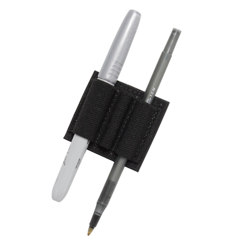 May include: Black nylon pen holder with two pens inserted. The holder has three elastic loops to secure the pens. One pen is silver and the other is black.