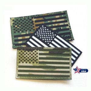May include: Three embroidered patches featuring the American flag. One patch has a digital camouflage pattern in shades of green and brown. Another patch has a black and white design. The third patch has a green and brown camouflage pattern.
