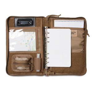K&ouml;nnte beinhalten: Offenes, braunes Notizbuch mit Rei&szlig;verschluss, einer durchsichtigen Tasche f&uuml;r eine Karte, einer Rei&szlig;verschluss-Netztasche, einem Stifthalter, einer schwarzen Klemmbrett und einem spiralgebundenen Notizbuch mit kariertem Papier. Der Notizbuchumschlag tr&auml;gt den Text "Tactical Notebook Covers.com".