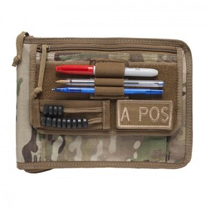 May include: A brown and tan camouflage notebook with a zipper closure. The notebook has a black elastic band, a black pen holder, and a tan patch that says "A POS".