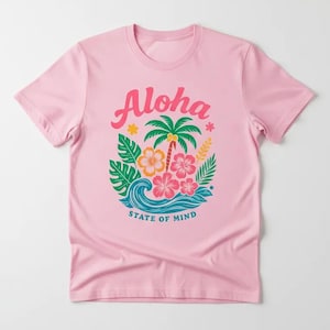 A pink t-shirt with a graphic design featuring a palm tree, flowers, and a wave, along with the text "Aloha State of Mind".