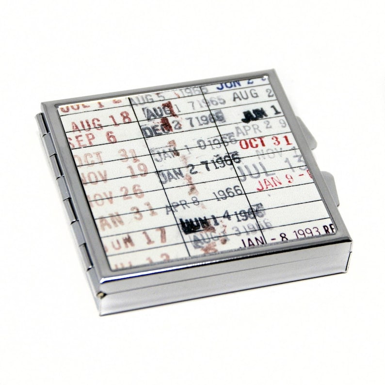 A metal coin or card holder with a calendar-like design on its surface, featuring dates and events printed on it.