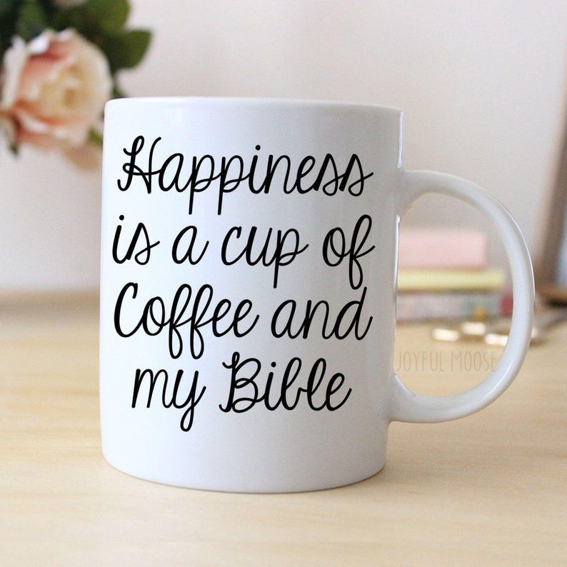 A white ceramic mug with the text "Happiness is a cup of coffee and my Bible" printed on it.