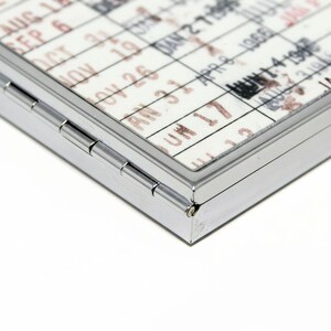 a close-up view of a metal object with a calendar-like pattern printed on it, featuring a grid-like design with dates and possibly other text.