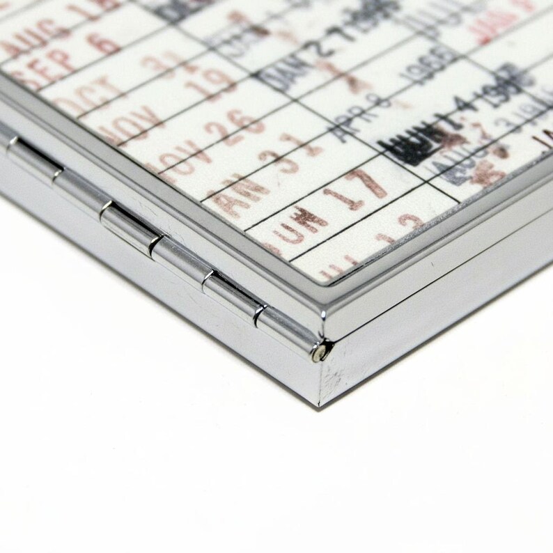 a close-up view of a metal object with a calendar-like pattern printed on it, featuring a grid-like design with dates and possibly other text.