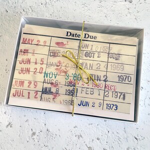A white box containing a stack of yellowed, handwritten date due cards.