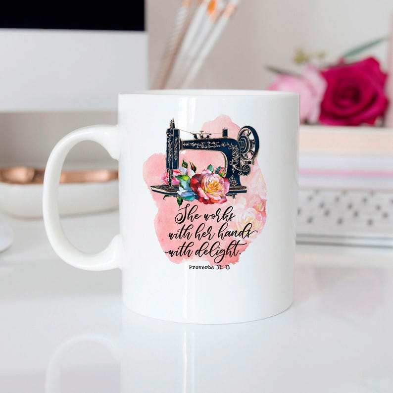 A white ceramic mug with a printed design featuring a sewing machine and flowers, along with a Bible verse from Proverbs 3:13.