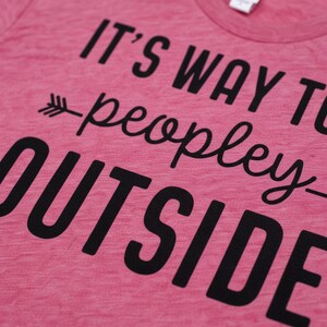 A pink t-shirt with black text that reads "IT'S WAY TO PEOPLEY OUTSIDE".