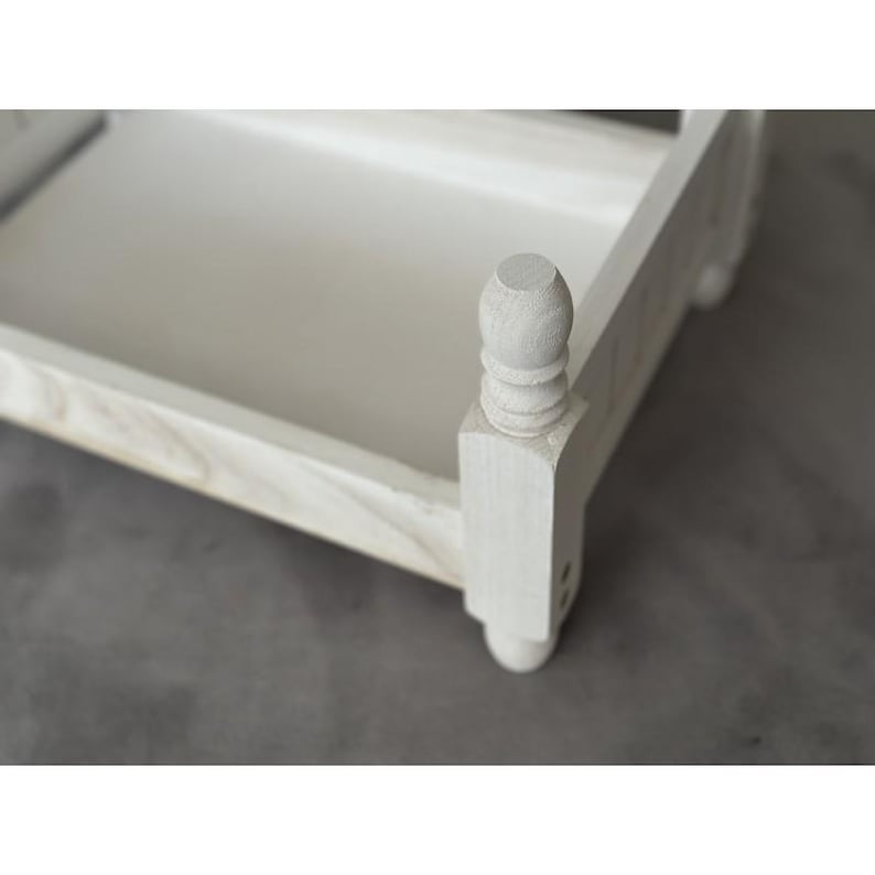 Puede incluir: Una peque&ntilde;a bandeja de madera pintada de blanco con un borde elevado y postes torneados decorativos. La bandeja tiene forma rectangular y una superficie lisa y pintada. El dise&ntilde;o es simple y elegante, adecuado para servir o exhibir.