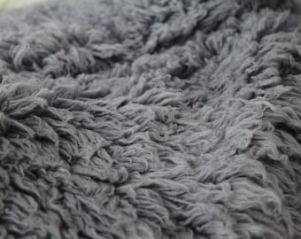 May include: Close-up of a soft, gray, fluffy rug with a textured surface.