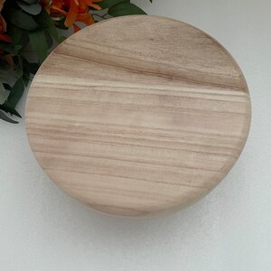 Puede incluir: Una bandeja redonda de madera para servir con un patr&oacute;n de veta de madera marr&oacute;n claro.