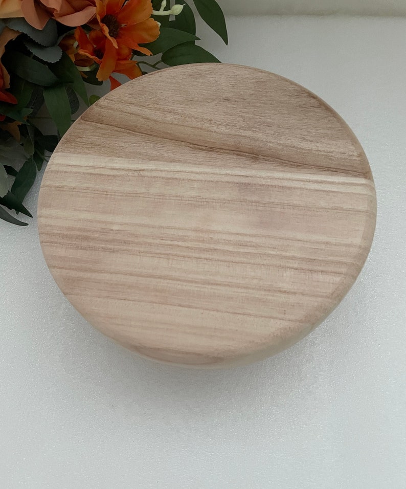 Puede incluir: Una bandeja redonda de madera para servir con un patr&oacute;n de veta de madera marr&oacute;n claro.