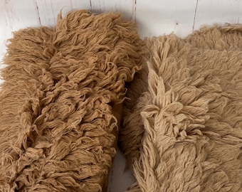 May include: Two fluffy brown throw pillows with a shaggy texture. The pillows are made of a soft, plush material.