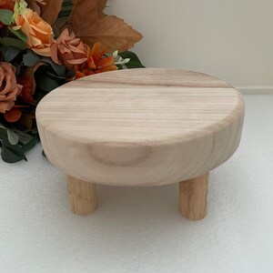 Puede incluir: Un pedestal redondo de madera con tres patas. El pedestal est&aacute; hecho de madera clara y tiene un acabado liso y natural.