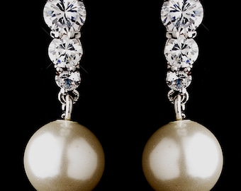 May include: Silver tone drop earrings with a single large faux pearl and three clear cubic zirconia stones.