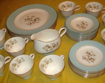 May include: A set of vintage teacups and saucers with a floral pattern. The cups and saucers are white with a light blue rim and a gold trim. The floral pattern is in shades of brown and gold.