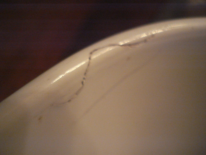 May include: Close-up of a white ceramic surface with a thin black line running across it.